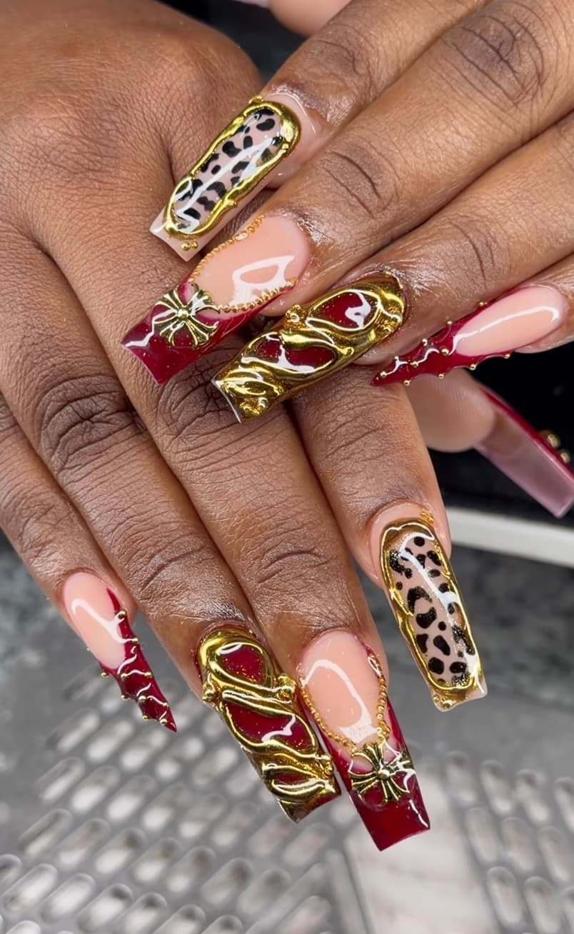 Red and gold leopard-print nail art with charms